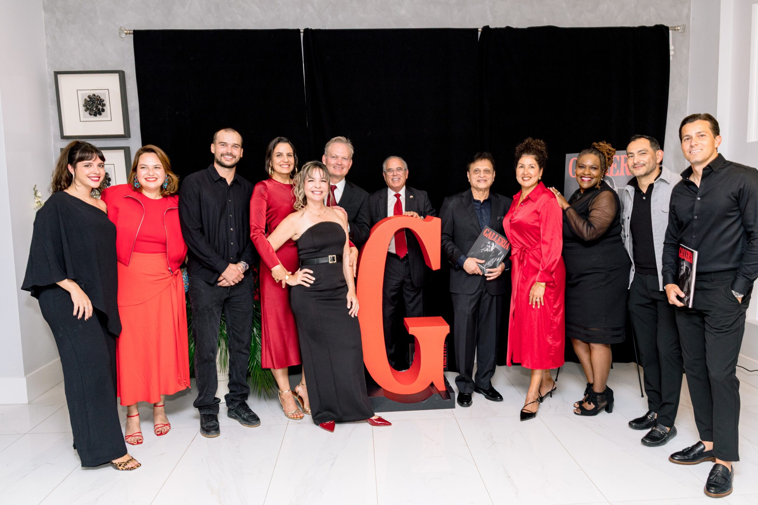 The Galleria team and guests in black and red, gathered around a large red letter G at the first-issue launch.