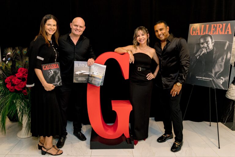 Four guests at the red G, holding the first print issue; the cover poster on an easel behind them.