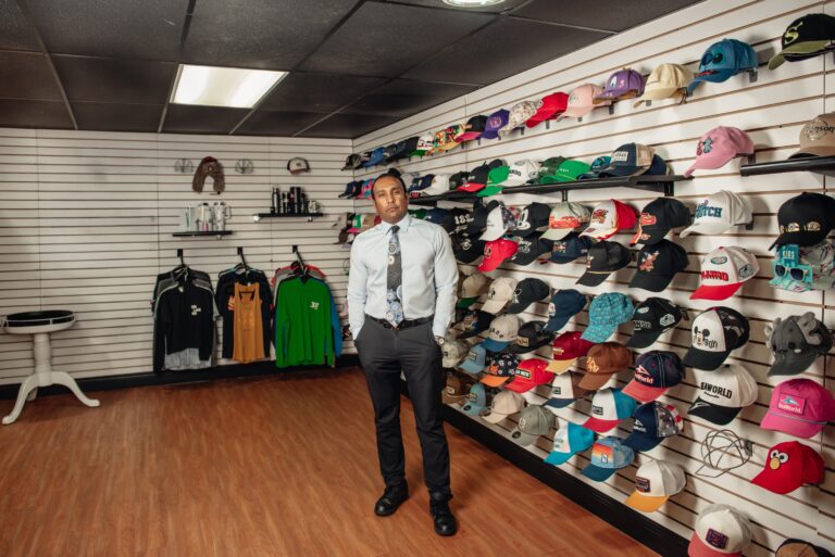 Sanjay Srinivasan in the Global Promo showroom, beneath walls of branded caps and merchandise.
