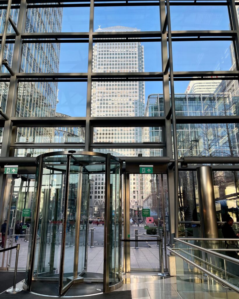 A revolving glass door at the entrance of a Canary Wharf office tower