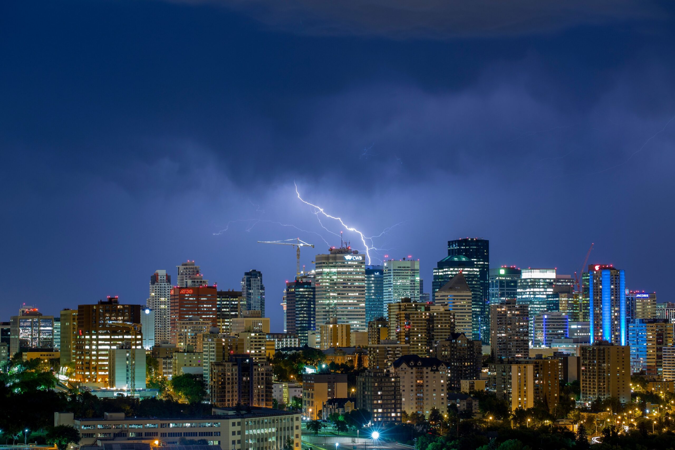 A lightning bolt splits a violet night sky above a lit downtown skyline.