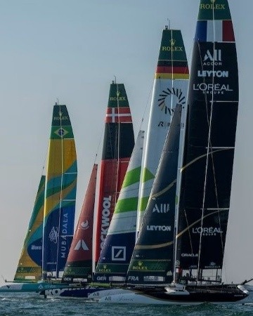 A row of F50 wingsails in national colors on the water, France's black wing nearest