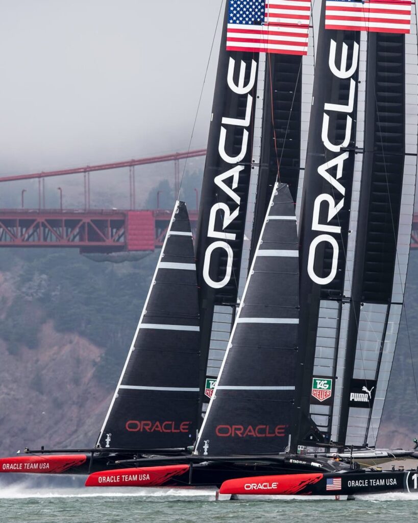 Oracle Team USA's two wing-sailed catamarans racing beneath the Golden Gate Bridge
